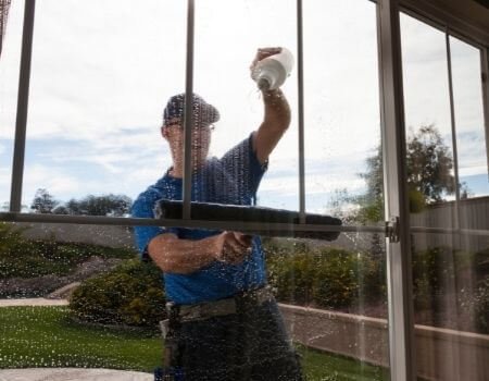 A man cleaning a window with a squeegee.