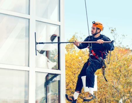 A man in safety gear cleaning a window, ensuring a spotless and clear view.