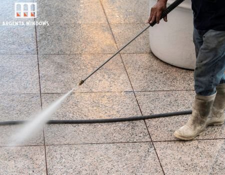 Man cleaning tile floor with pressure washer.